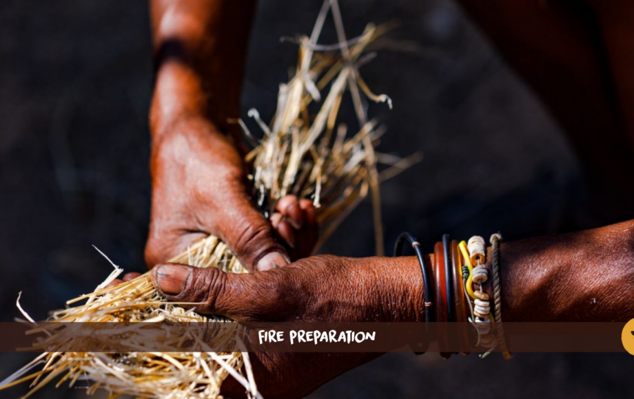 Two black hands with bracelets hold dry grass.