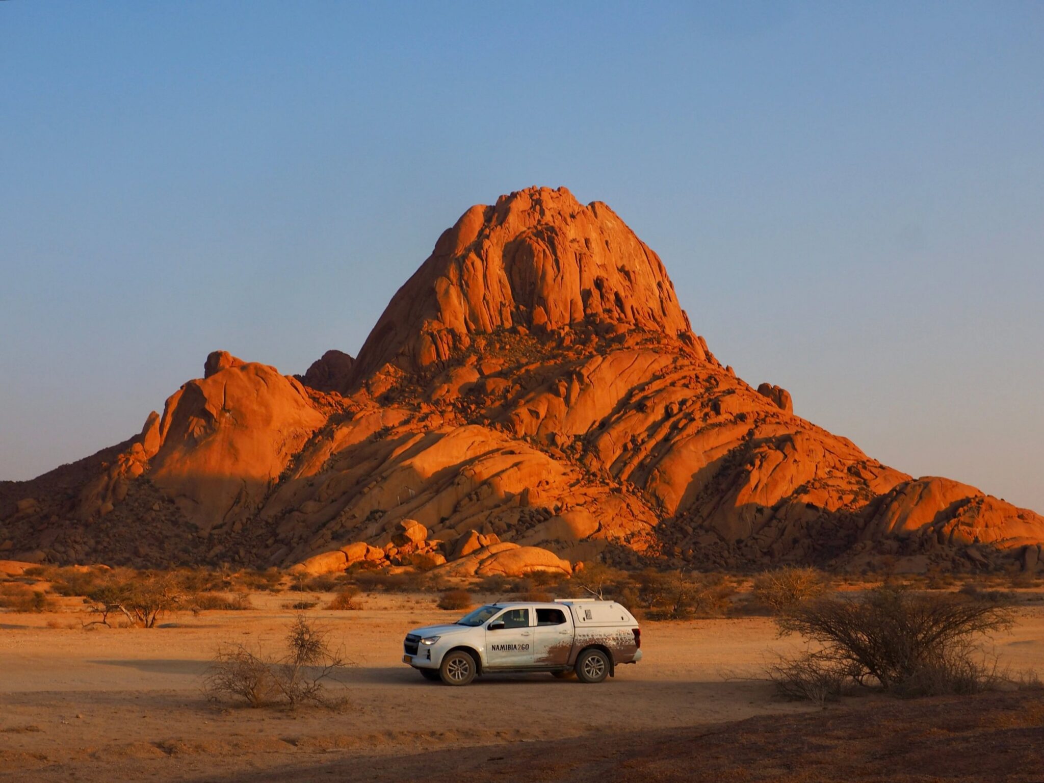 Safarivoertuig geparkeerd bij Spitzkoppe tijdens zonsondergang
